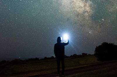 Man standing by a telescope looking up at the milkyway (Image Credit unsplash)